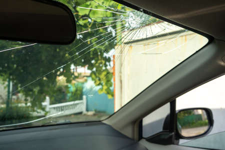 broken windshield with a lot of cracks and small glass pieces, damaged carの写真素材
