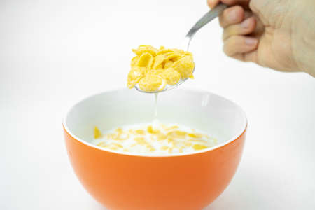 dry cornflakes in a bowl with milk, spoon on white background, healthy food