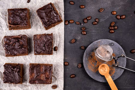 Cocoa brownies pouring with melted dark chocolate cut out to square pieces. Black background. Top view flat layの写真素材