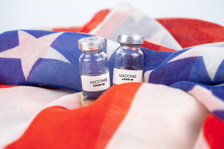 Two bottles with covid-19 vaccine. US flag on backgroundの写真素材