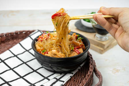 Asian salad with rice noodles, vegetables, mushrooms, chicken and soy sauce. Funchose with white transparent noodles in black plateの写真素材