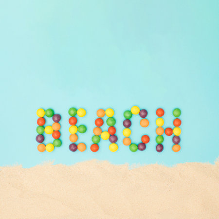 Beach word made from colored balls  on a blue background with sand. Tropical summer beach concept on a minimal background.の写真素材