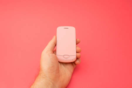 Hand holding pink 3d smartphone against red background. 3D illustration design template background. Top mobile phone message. Advertisement idea. Empty copy space for adの写真素材