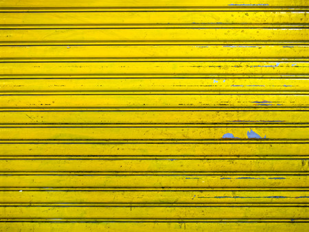 close up of grunge bright yellow roller shutter door texture backgroundの写真素材