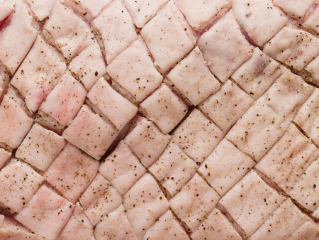 close up of raw uncooked seasoned scored pork belly skin backgroundの写真素材