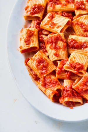 close up of a plate of rustic italian paccheri pasta in tomato sauceの写真素材