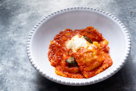 close up of a bowl of italian ravioli pasta in tomato sauceの写真素材