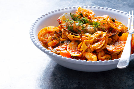 close up of a bowl of italian seafood pasta in tomato sauceの写真素材