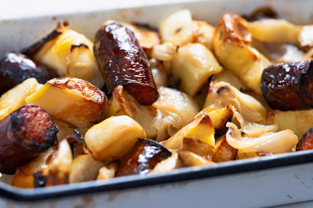 close up of a tray of baked sausages and potatoesの写真素材
