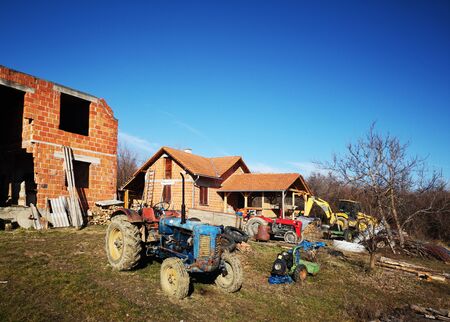 Old rusty blue and red vintage tractors in a farmの写真素材