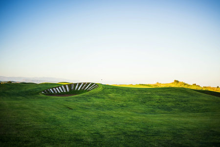 Beautiful golf course with sand trap at sunsetの写真素材