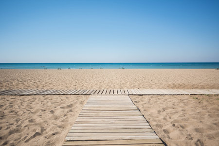 Wooden walkway on the sandy beach of the sea under the blue skyの写真素材