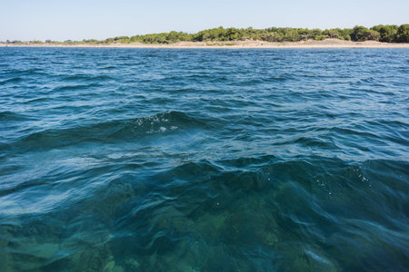 Waves in the Mediterranean sea with land in the backgroundの写真素材
