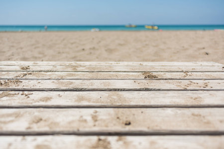 Sandy beach on sunny day with wooden walkway close-up