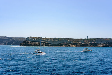 Boats with tourists near Santorini islands in a deep blue sea. Tiny little houses on top of the islands. Greece in summer.の写真素材