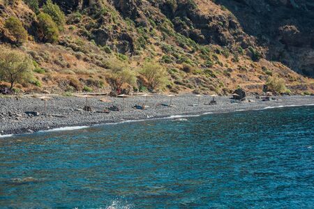 Small Nisyros beach with a very few DIY sunbeds with umbrellasの写真素材
