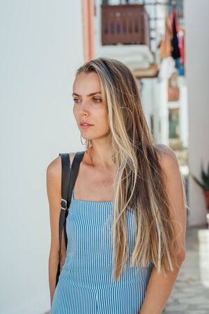 Young beautiful woman in blue dress posing on a narrow street at Nisyros island, Greece.の写真素材