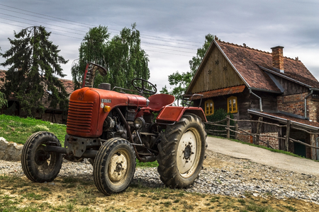 Rustic tractor and house on a cloudy dayの写真素材