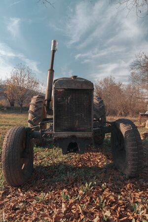 Old vintage rusty broken tractor in a field on a sunny dayの写真素材