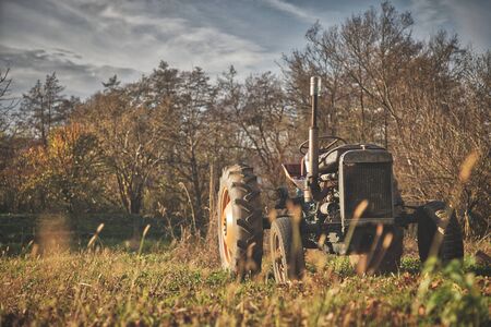 Old vintage rusty broken tractor in a field on a sunny dayの写真素材