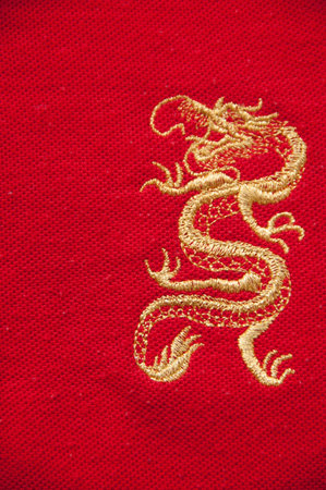 The golden dragon in golden thread sewed on the red fabric の写真素材