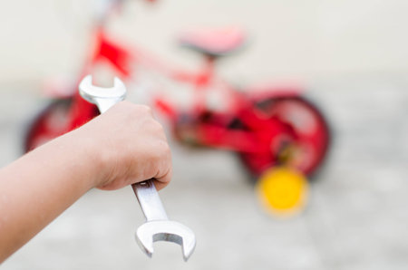 The child want to repair the bicycle and  holding the wrench in the hand.の写真素材