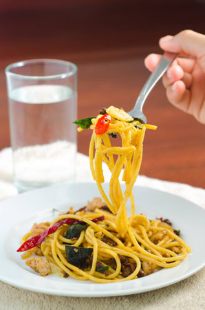 The menu of Fried spaghetti with chili with shellfish served in the white dish and someone is eating.の写真素材