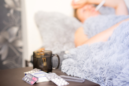 tired woman girl lies on the bed under a warm blanket.の写真素材
