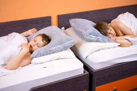 The child lies under a blanket with a fever.の写真素材