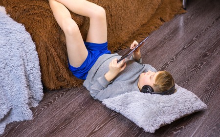 The child lies on the floor and plays on the laptop.の写真素材