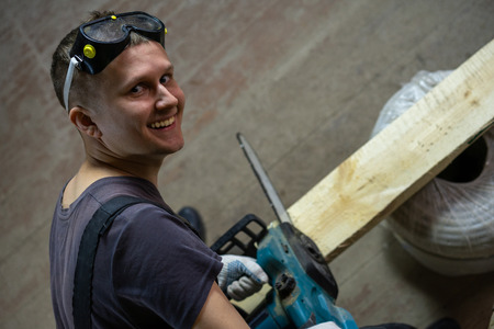 Professional construction worker continues to make repairs. He is smiling cheerfully.