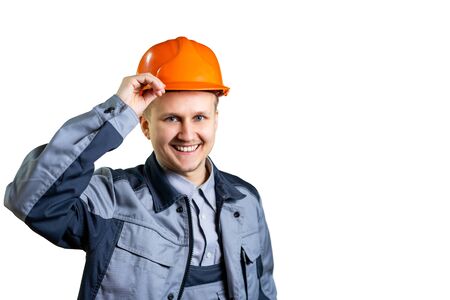 Portrait of a young builder worker in an orange helmet. He welcomes you to the camera. Repair and construction. isolated. Close-upの写真素材