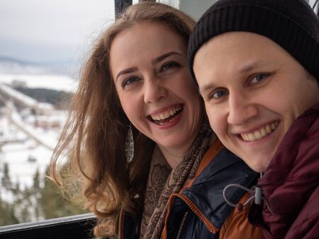 A young couple laughs a lot on one beautiful winter day. This is such a family happiness.