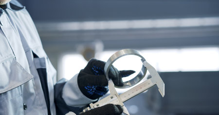 A mechanic using a vernier caliper to measure a piston rod or engine part.