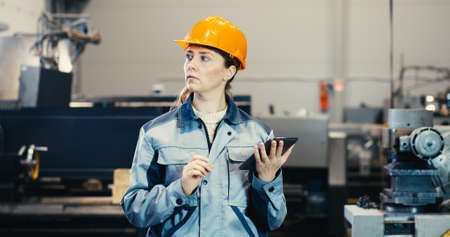 Senior engineer girl in a worker suit and helmet works on a tablet pcの写真素材