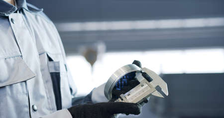 Man verifies the accuracy of manufacturing steel parts with a special caliper Additional scale - the size of the measurement device.の写真素材