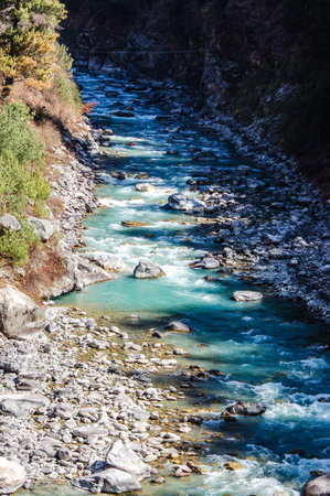 A blue river runs through a valley on the everest base camp trekking route on sunshine day.