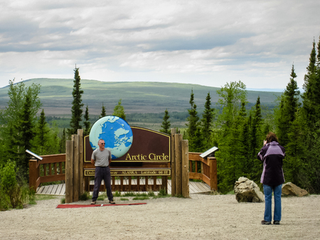 Alaska, USA - May 29, 2009: A couple took a photo with the arctic circle sign which was a destination of one day tour on Dalton highway.のeditorial素材