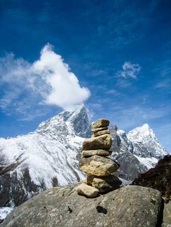 Stone cairn with high snow mountain in himalayas on a bright blue sky day.の写真素材