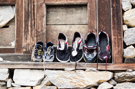 Sports shoes with different sizes were placed against the wooden wall for drying outside the house on the way to Everest base camp in himalayas.の写真素材