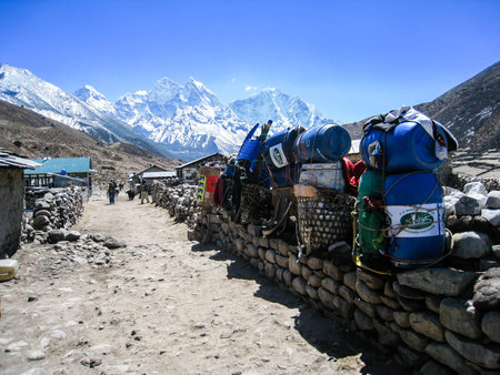 Belongings was placed on a stone wall in a village of himalayas with high snow mountains on background, waiting for transport to their destinations in a blue sky day.のeditorial素材