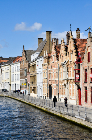 Bruges, Belgium - April 15, 2010: Tourists were walking pass the traditional Belgian houses on a riverbank of a canal in a quiet residential area of Bruges on a sunny day.のeditorial素材