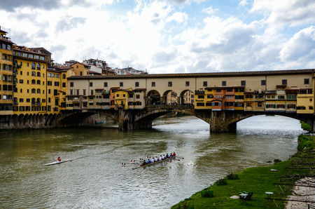 Florence, Italy - April 10, 2011: Rowers rehearsal on  the Arno river of Florence, Italy and Ponte Vecchio, the landmark bridge, in white cloud and blue sky.のeditorial素材