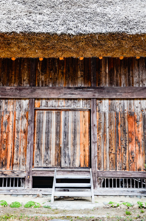 Thatched steep roof detail and wooden wall and door of traditional gassho zukuri house at historic Shirakawa-go village in Gifu, Japanのeditorial素材