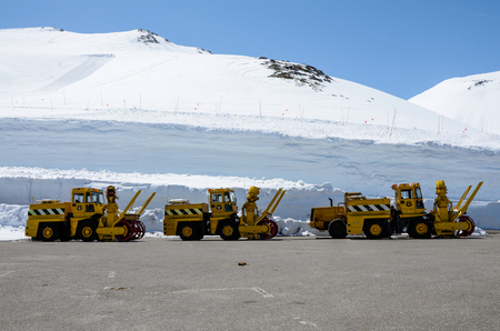 Yellow tractors parked beside the snow wall at Murodo of Tateyama Kurobe Alpine Route (Japan Alps), Toyama city, Japan in blue sky on sunshine.の写真素材