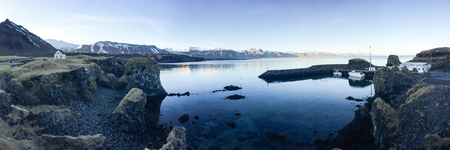 Panorama view of Port Arnarstapi, a small village at Snaefellsnes peninsula, west coast of Iceland on blue sky sunshine with a backdrop of mountains.の写真素材
