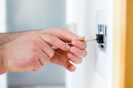 Man installing light switch with screwdriver after home renovationの写真素材