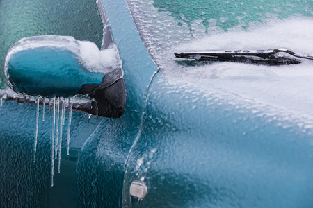 Frozen rearview mirror and wiper of the car with icicles, ice and frostの写真素材