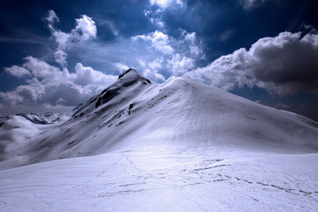 Snowy  and shiny mountain top with footsteps in the foregroundの写真素材