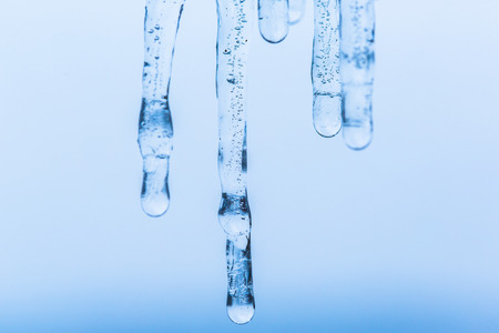 Icicles melting, detail on a blue backgroundの写真素材